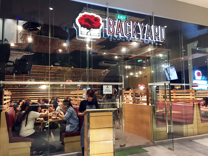 View in front of Backyard Kitchen and Brew with people inside eating and chatting