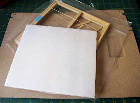 Pieces of a dollshouse building kit with a sliding door unit on top, covered with a piece of card.