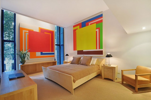 Photo of the same bedroom with wooden furniture and apstract art on the walls