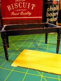Miniature dining table leg assembly, painted black, sitting on a cutting mat with a spray can of chalkboard paint.