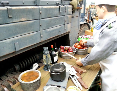 1/6 scale German soldier preparing food in a diorama of an army post on display at a scale model exhibition.