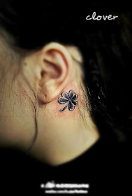 a delicate small four-leaf clover tattoo behind the ear