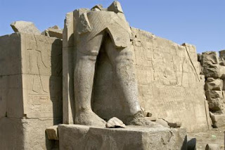 ruin of a sandstone statue with only legs left
