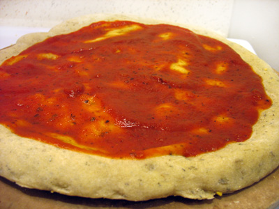 pizza dough with sauce spread on.