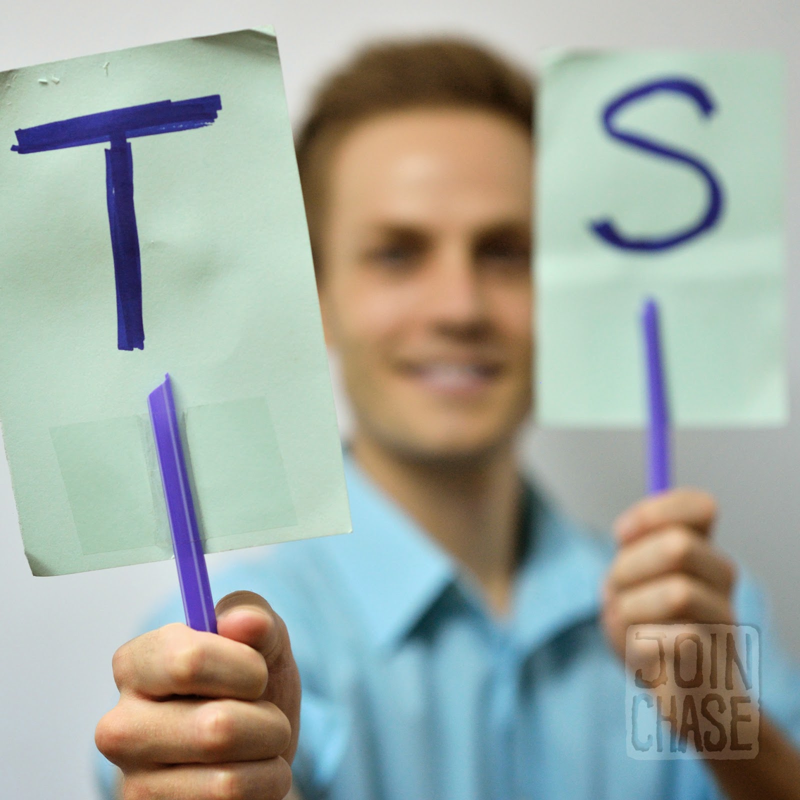 A teacher holding couplet visuals to use during the practice portion of an English lesson.