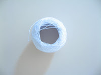 Top view of cardboard reel of white size 80 cotton thread.