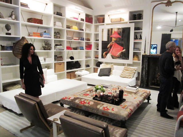 Family room in the windsor house with white built in bookshelves, a large piece or art in a white frame, Barcelona club chairs, a white ottoman, a fireplace and a large vintage mirror in a gold frame