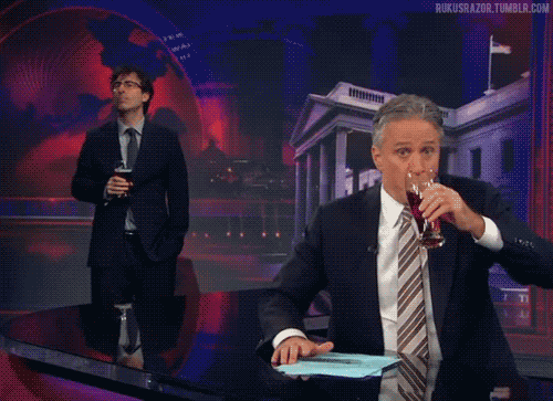 Animated gif of Jon Stewart and John Oliver doing spit takes one after another