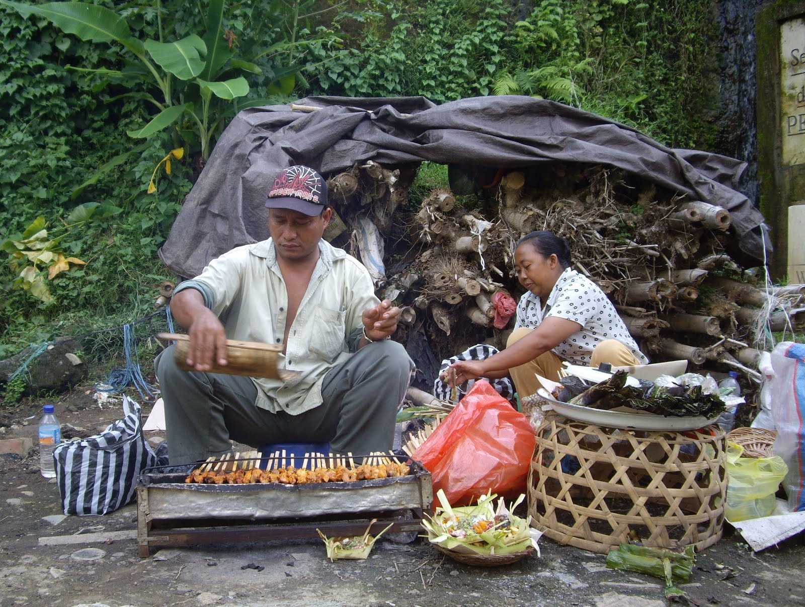 FANNING AND COOKING CHICKEN SATE STICKS ON THE SIDE OF THE ROAD.  UBUD, BALI