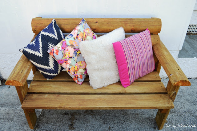 outdoor wooden bench with colourful pillows by Amy MacLeod
