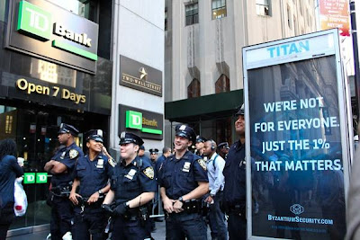 Photo of four unformed cops laughing beside a kiosk poster that reads We're not for everyone, just the 1% that matters