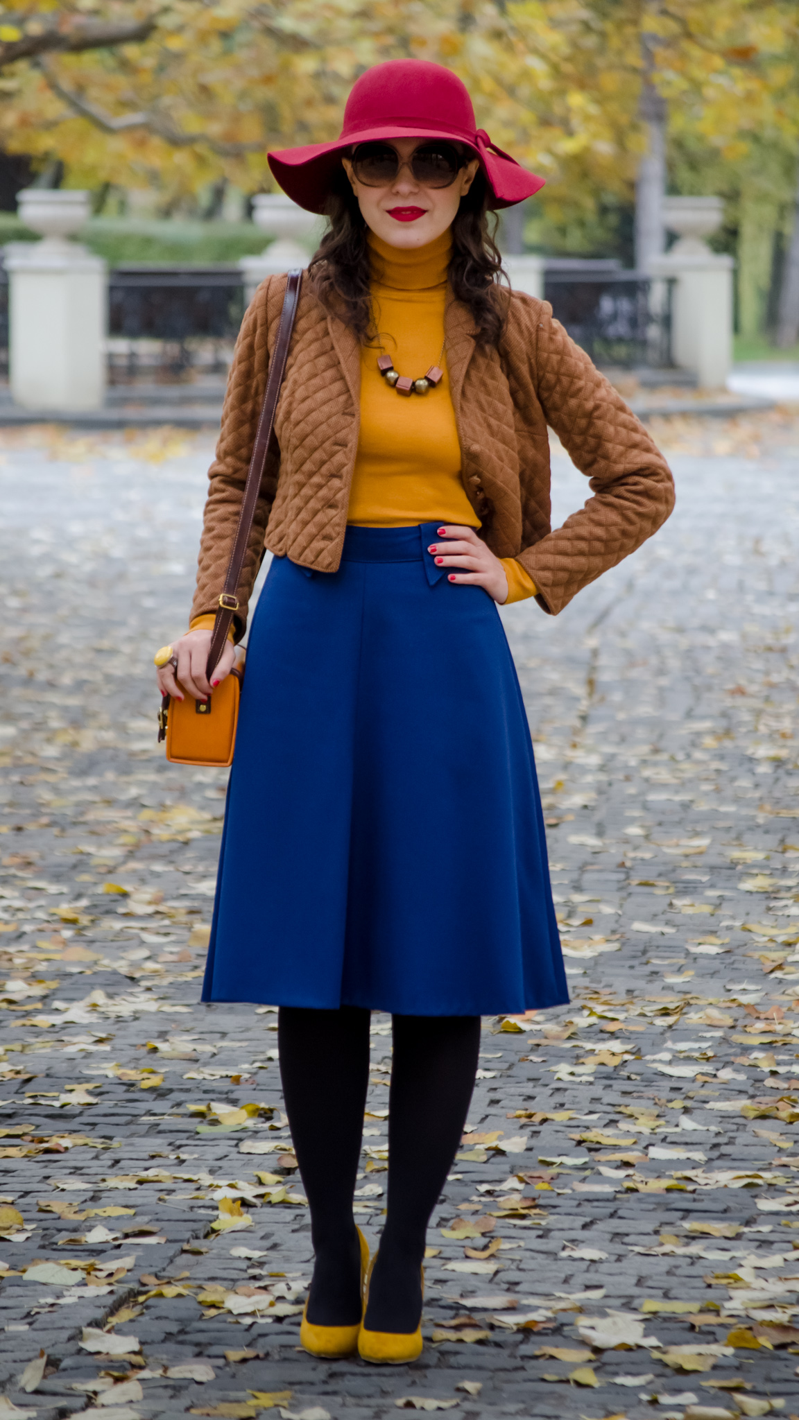 blue skirt mustard turtleneck sweater burgundy floppy hat brown jacket box satchel mustard heels autumn fall scenery leaves