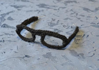 A pair of black crocheted glasses.