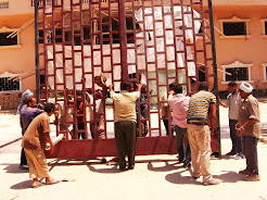 مجموعة من العمال تجاهد لرفع بوابة مجمع شرطة ملوى قبل افتتاح مجمع الشرطة صيف عام 2012 تقريبا