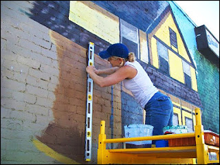 Raette works on a building-size mural painting