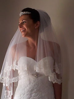 Smiling, happy bride with lace wedding dress, lace cathedral veil 