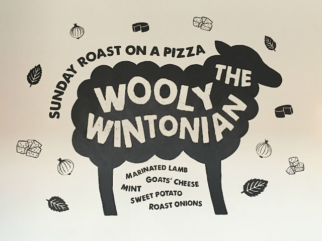 Sign writing on a wall advertising the Woolly Wintonian pizza