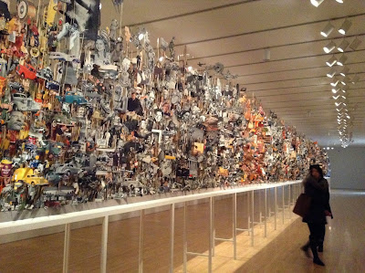 Person walks by art installation made up of thousand of magazine pictures. 
