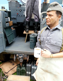 1/6 scale German soldier drinking coffee in diorama of an army post on display at a scale model exhibition.