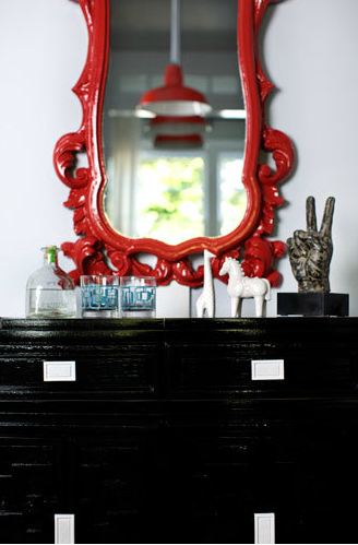 Glossy black chest of drawers with a red traditional mirror