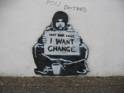 Meek stencil art of man sitting holding sign that says "Keep your coins. I want change"  Someone else has written "you bastard" above it
