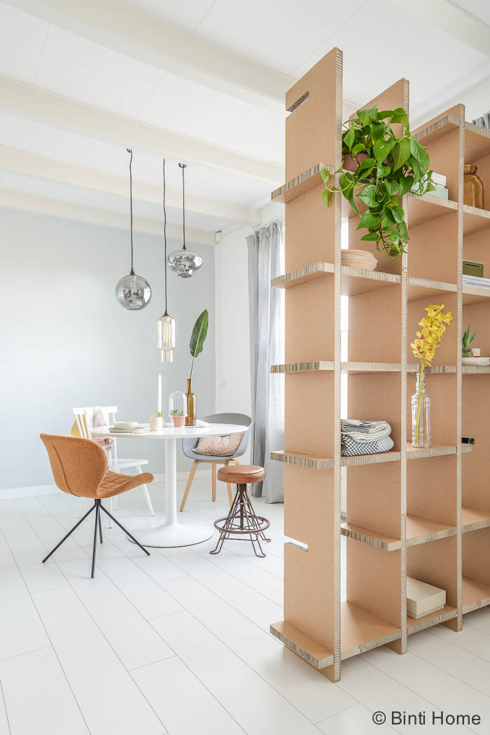Een doorkijk naar de ronde tafel en een mix van stoelen binti ...