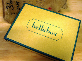 Small cardboard box labeled 'bellabox' on top of postal wrapping.