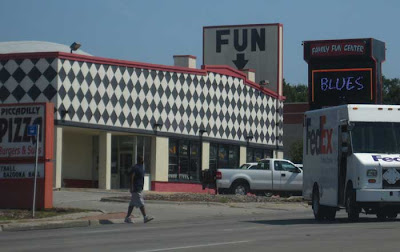 Black and white harlequin checked building with sign above saying just FUN with an arrow pointing downward