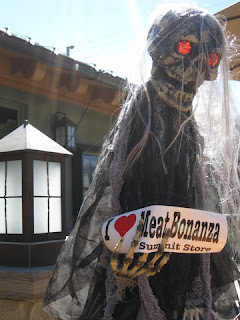 Ghoul with glowing red eyes, holding a sign "I (heart) Meat Bonanza, Summit Store," Los Gatos, California