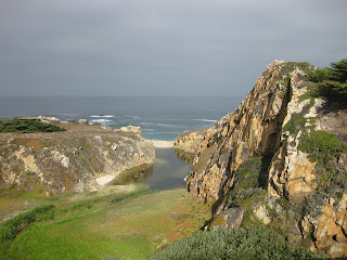 Sunlit cove against a gray sky along the Pacific Coast Highway