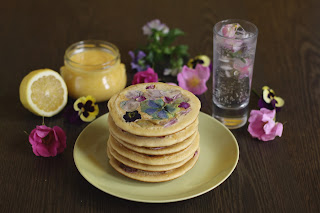 Deliate pancakes with edible flowers in the batter accompanied by homemade lemon curd - recipe brought to you by the german foodblog Pancake Stories!