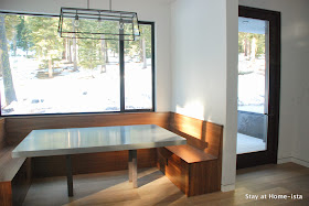 Window wrapped dining nook with walnut benches and a zinc table