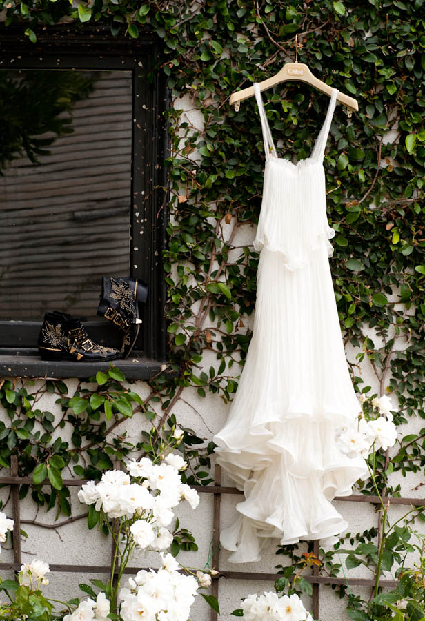  white Chloe gown hangs on a trellis of roses in a Los Angeles garden