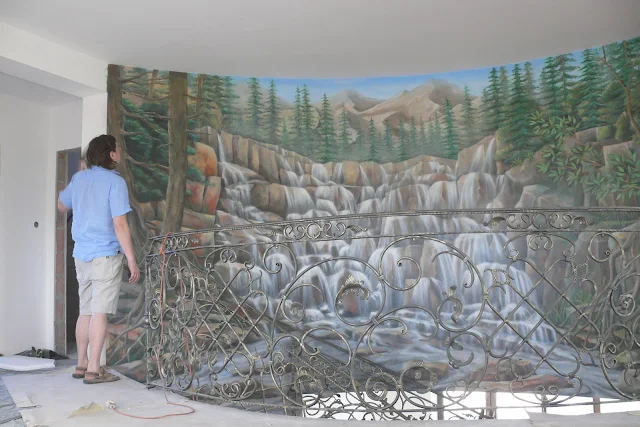 Obraz namalowany na ścianie przedstawia wodospad, potok górski malowanie