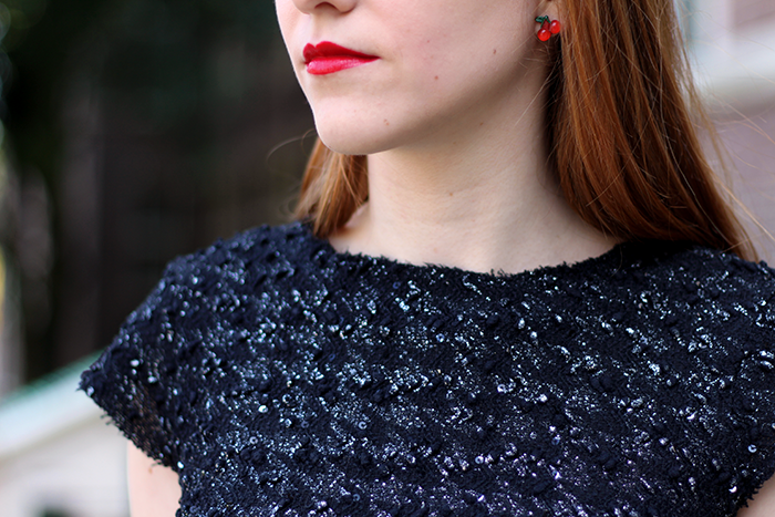 Blogger outfit detail with tweed houndstooth top, red lipstick and cherry earrings