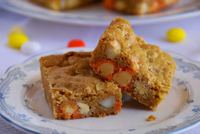 close up of two candy corn M&M, roasted macadamia nut, and sea salt blondies on a small plate