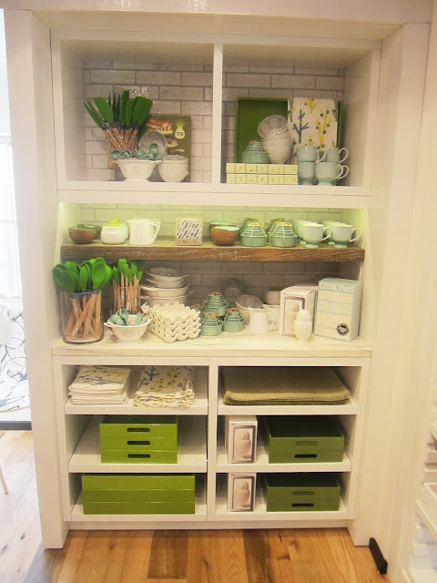 White cabinet holding kitchen accessories in a variety of shades of green