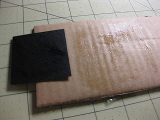 Applyign rubber cement to the cardboard base for the LED paper lamp. 