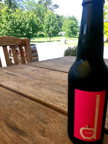 Bottle of Dcider on a patio table  in a garden.