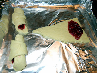 Rolled out crescent rolls dough smeared with cranberry sauce