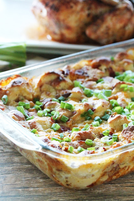 Loaded Baked Potato Stuffing in a casserole dish, fresh out of the oven. Garnished with sliced green onions.