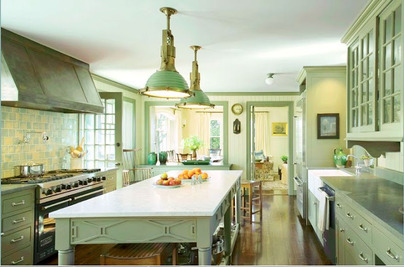 Traditional ktchen by Michael S. Smith with green and yellow backsplash, green cabinets and drawers, an island under two pendant lights and a hardwood floor