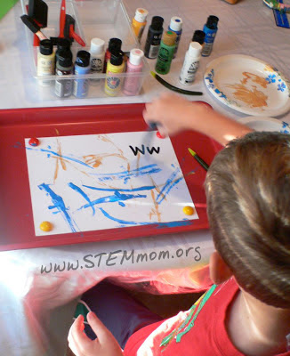 Boy painting art piece using rubber worms: STEMmom.org 