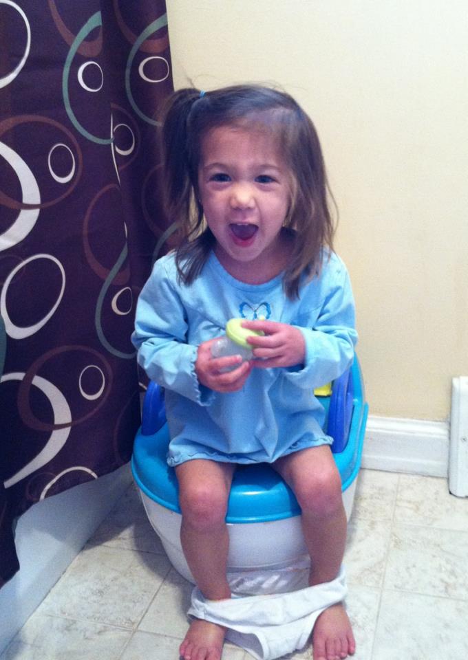A mother introduces her two-year-old daughter to toilet 