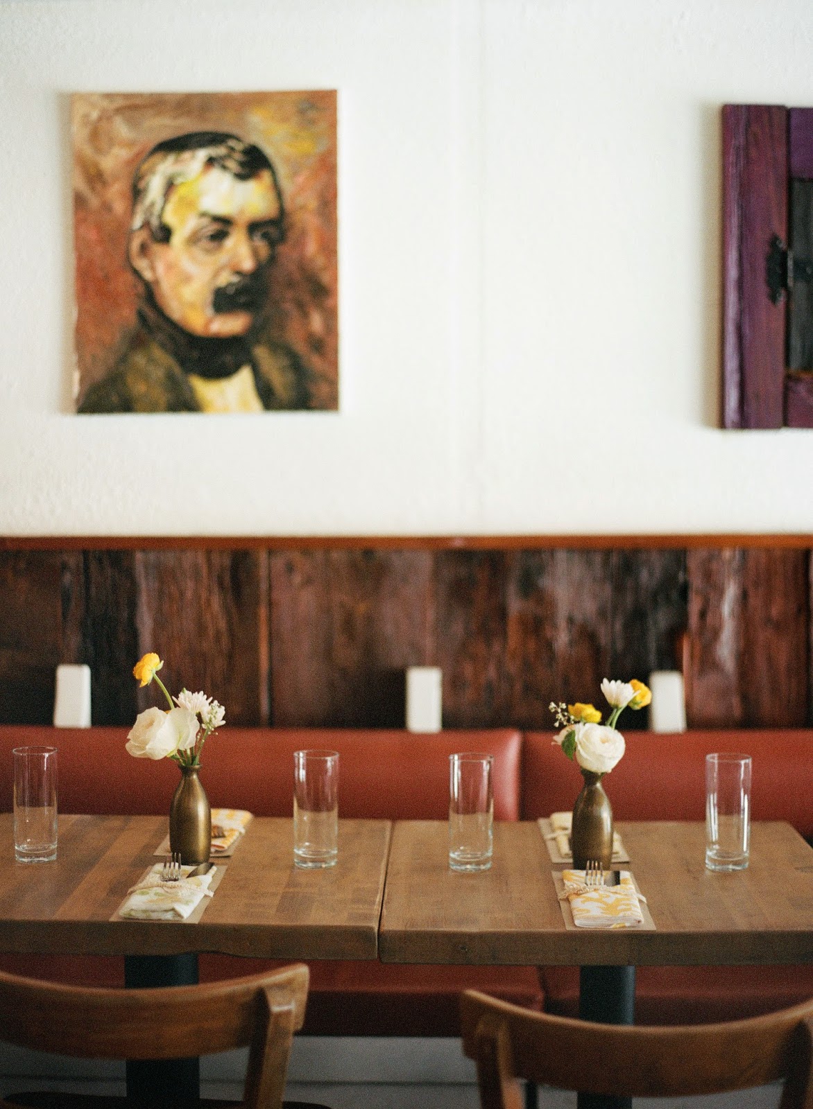 yellow and white spring wedding flowers in antique brass vases with vintage portraits at an intimate brooklyn, new york restaurant wedding dinner