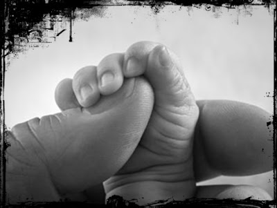 Baby holding mother's thumb
