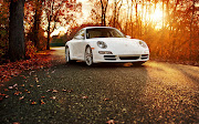 . 911 blanco que que esta en la calle rodeado de arboles durante el otoño. bello carro en la carretera de otoã±o