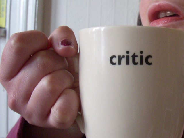 A girl holding a cup with 'Critic' written on it