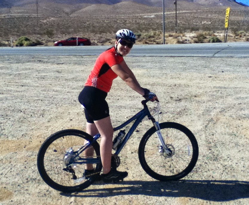 Rachel posed on a mountain bike on the side of the road in the desert. 