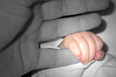 Hand eines Baby umschließt einen kleinen Finger